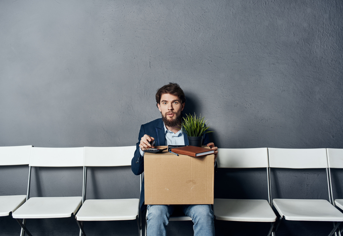 A Man with Things in a Box Sits on a Chair Waiting for Discontent
